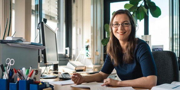 Julia Tjus sitzt am Schreibtisch.