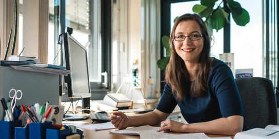 Julia Tjus sitzt am Schreibtisch.
