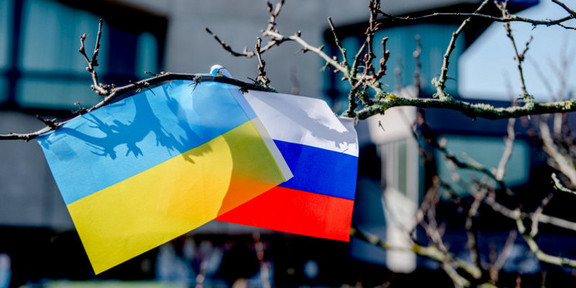Ein Ast an dem eine ukrainische und eine russische Flagge nebeneinander hängen.