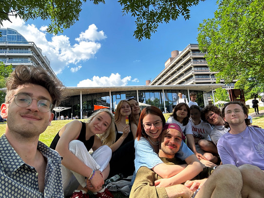 Gruppe von internationalen Studierenden, die auf einer Wiese auf dem RUB-Campus sitzt