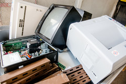 An old computer and an old printer lying on paper waste