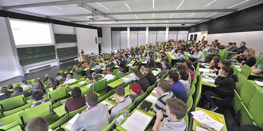 Studierende des Masterstudiengangs Medizinphysik in einem Hörsaal mit grüner Bestuhlung.