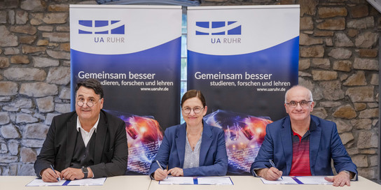 Drei Rektoren unterschreiben einen Vertrag.