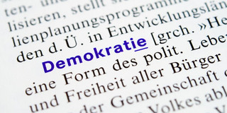 Book page with text; the word “democracy” is highlighted in blue.