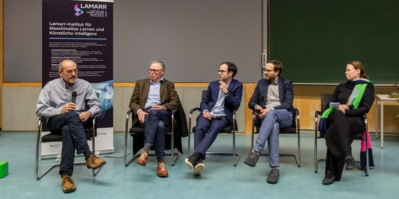 Fünf Forschende sitzen auf einer Bühne und diskutieren.