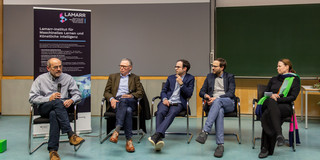 Five researchers sit on a stage and discuss.