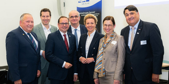 Ein Gruppenfoto mit zwei Frauen und fünf Männern in Anzügen, die in die Kamera lächeln. Das Foto zeigt (von links nach rechts): Josef Hovenjürgen, Parlamentarischer Staatssekretär im Ministerium für Heimat, Kommunales, Bau und Digitalisierung des Landes Nordrhein-Westfalen, Thomas Eiskirch, Oberbürgermeister der Stadt Bochum, Thomas Kufen, Oberbürgermesiter der Stadt Essen, Manfred Bayer, Rektor der Technischen Universität Dortmund, Ina Brandes, Ministerin für Kultur und Wissenschaft des Landes Nordrhein-Westfalen, Barbara Albert, Rektorin der Universität Duisburg-Essen, und Martin Paul, Rektor der Ruhr-Universität Bochum.