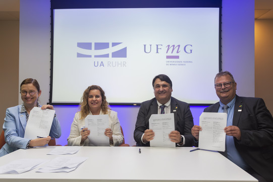 Four people in front of a screen with contracts in their hands