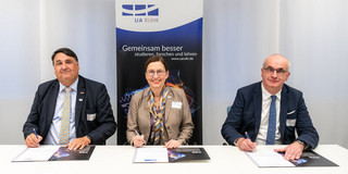 Photo: Two men and a woman in formal dress sit at a table and sign a declaration. Behind them hangs a banner of the UA Ruhr. The people are (from left to right): Joint signing of the Magna Charta Universitatum 2020 by the University Alliance Ruhr: the Rector of Ruhr-Universität Bochum, Prof. Martin Paul, the Rector of the University of Duisburg-Essen, Prof. Barbara Albert, and the Rector of TU Dortmund University, Prof. Manfred Bayer.