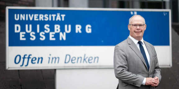 Portrait of Ulf Richter in front of the UDE logo