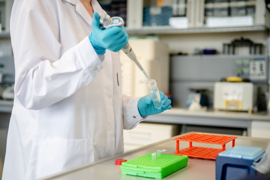 Person in the laboratory filling drops into small test tubes with a large pipette.