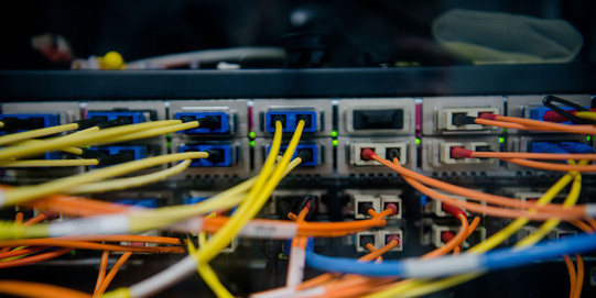 Rückseite eines Servers, aus dem ein buntes Kabelgewimmel herauskommt