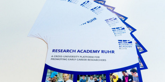 Nachwuchsförderung Flyer der Research Academy Ruhr, die gefächert auf einem weißen Untergrund liegen