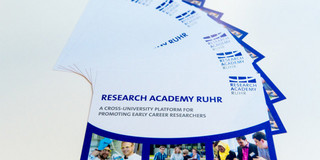 Nachwuchsförderung Flyer der Research Academy Ruhr, die gefächert auf einem weißen Untergrund liegen