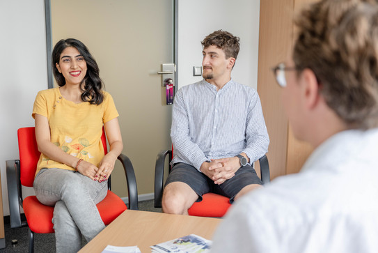 Eine Studentin und ein Student, auf Stühlen sitzend, bei einem Gespräch mit einer Person von der Studienberatung.