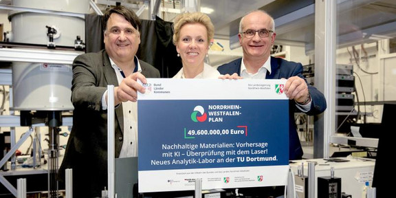 Drei Menschen im Labor halten einen Förderbescheid in den Händen.