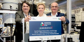 Drei Menschen im Labor halten einen Förderbescheid in den Händen.