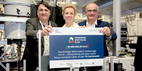 Drei Menschen im Labor halten einen Förderbescheid in den Händen.