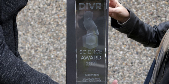 Das Bild zeigt den Science Award, der von zwei Personen gehalten wird.