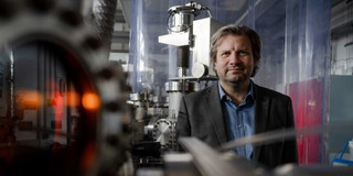 Foto: Prof. Alfred Ludwig steht in einem Labor. Im Vordergrund liegen Geräte.